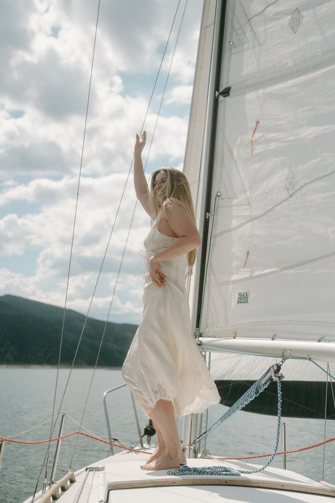 Lauren standing at the bow of the sailboat, arm raised to the sky