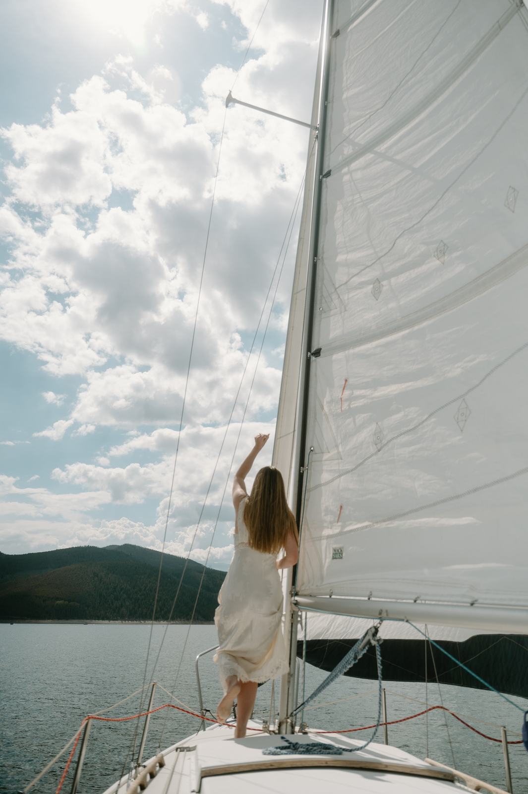 Lauren at the bow beneath a full white sail